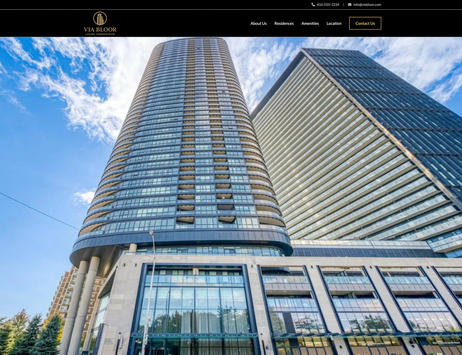Two tall modern residential towers with glass and metal facades against a blue sky with clouds