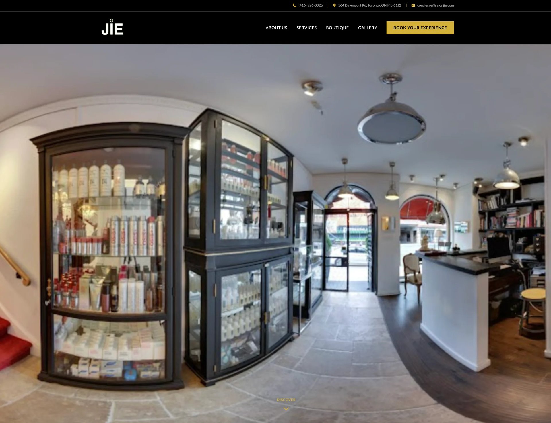 Interior of a modern beauty salon with display cases, products on shelves, white counter, and polished flooring