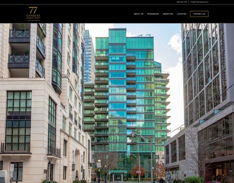 Modern turquoise glass residential tower surrounded by classical stone buildings on an urban street with cloudy sky